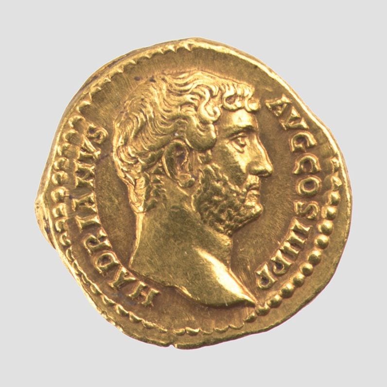 Gold Roman coin with the bearded head of the emperor Hadrian in profile and his name around the edge