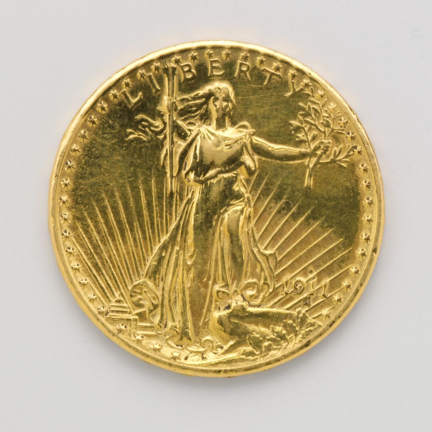 Gold twenty dollar coin showing Liberty striding forward holding a torch, with rays of sunlight behind her